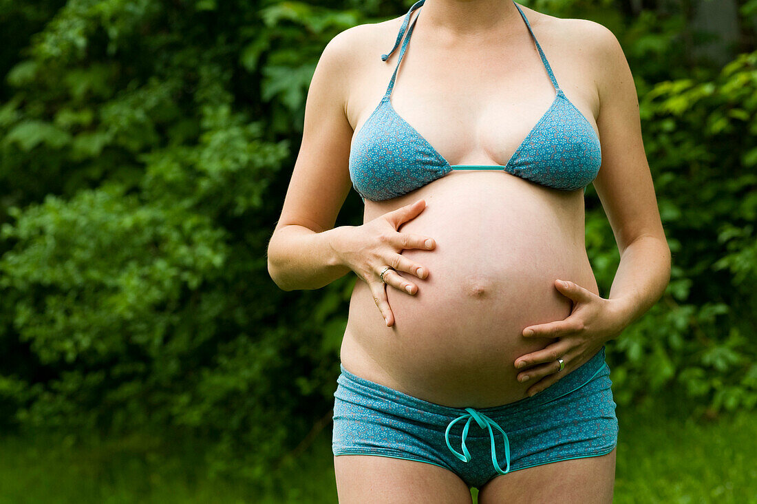 Frau, im neunten Monat schwanger, berührt ihren Bauch