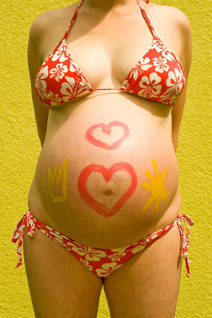 Frau, im neunten Monat schwanger, mit Körperbemalung auf ihrem Bauch