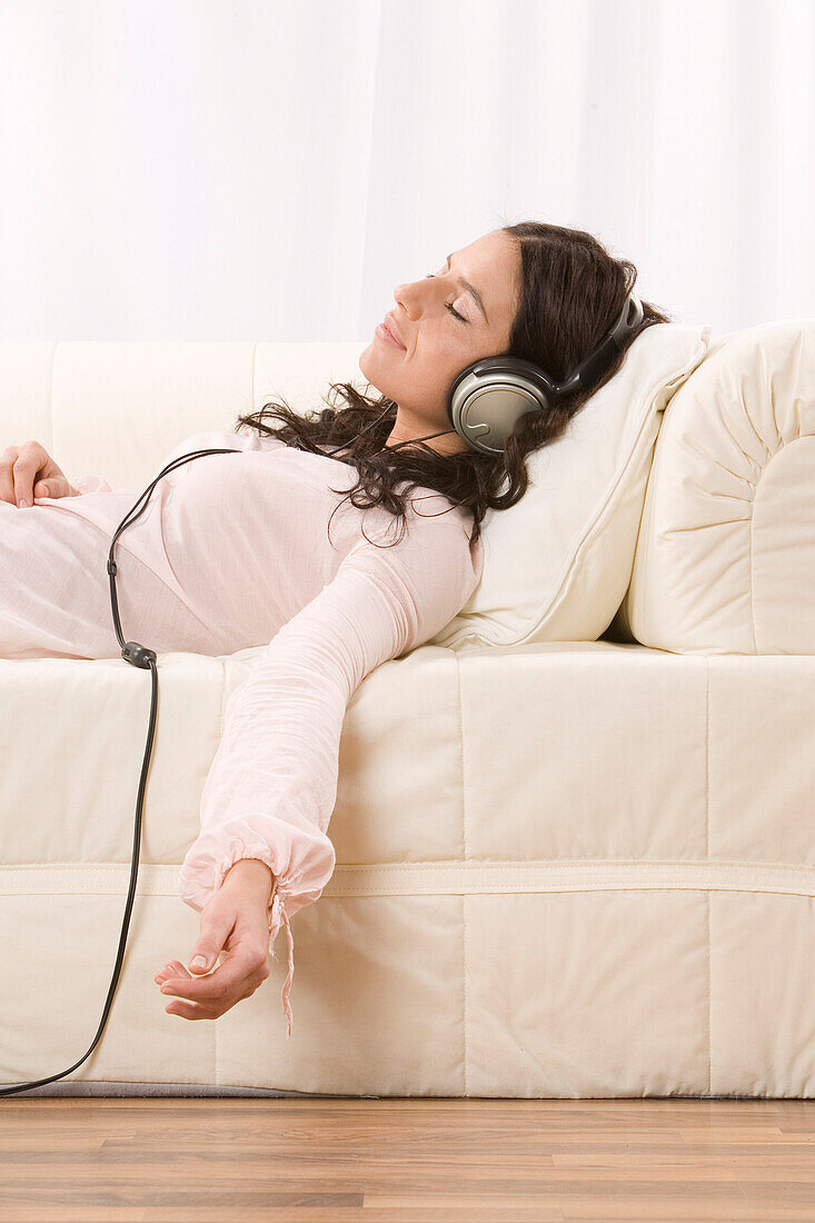 Woman Listening to Music with Headphones on Sofa