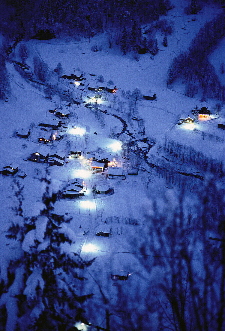 Übersicht von Häusern und Bäumen vom Berg bei Nacht im Winter, Schweiz
