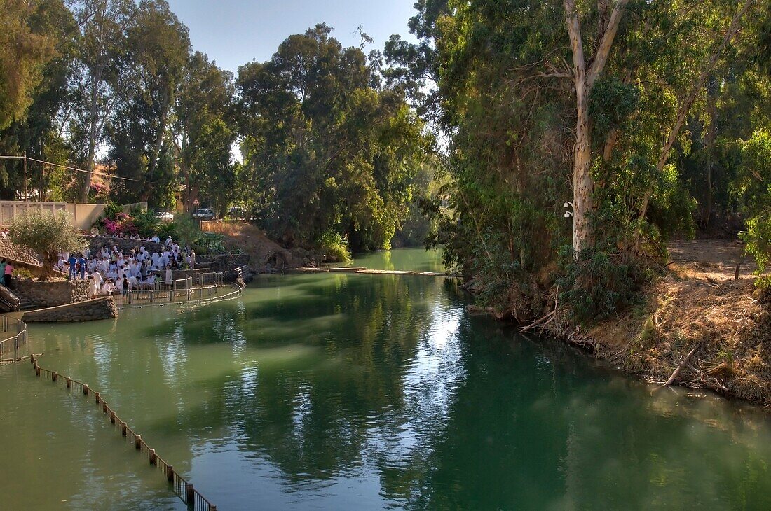 Trees Reflecting In River With People Gathered On Bank