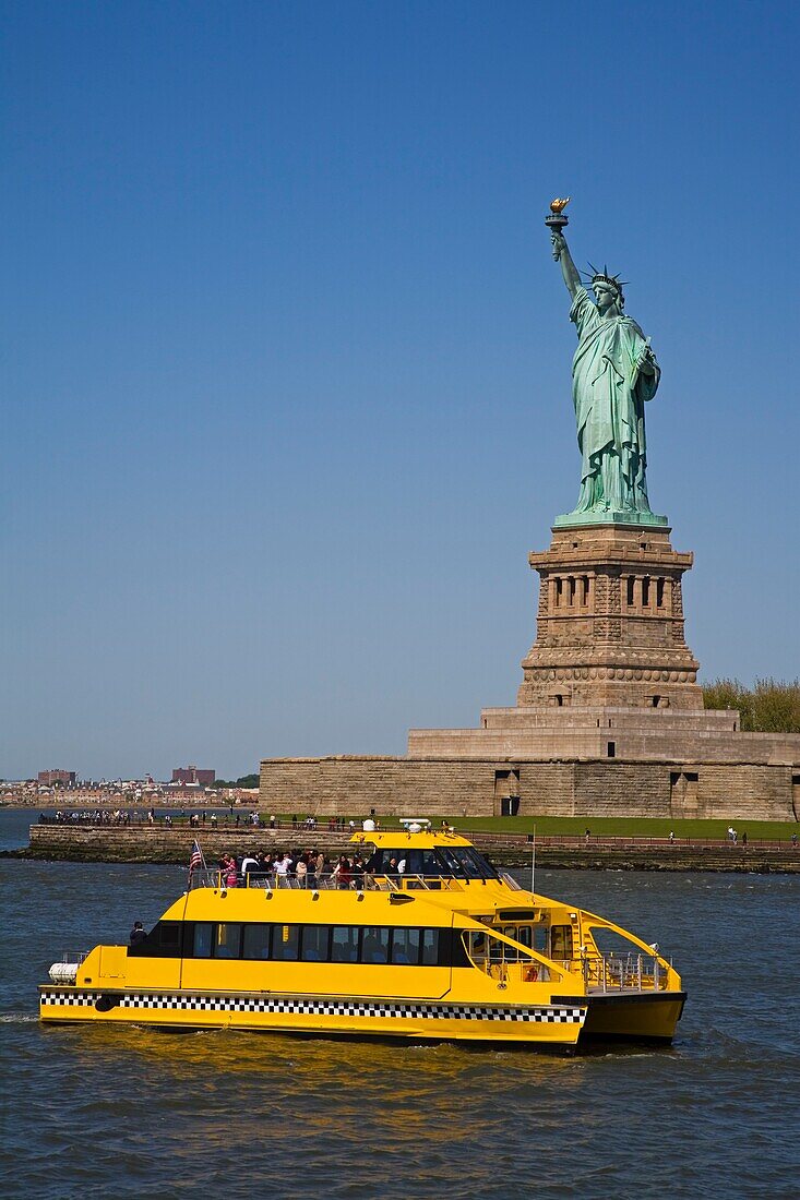 Water Taxi Passing Statue Of Liberty In Lower Manhattan; New York City, Usa