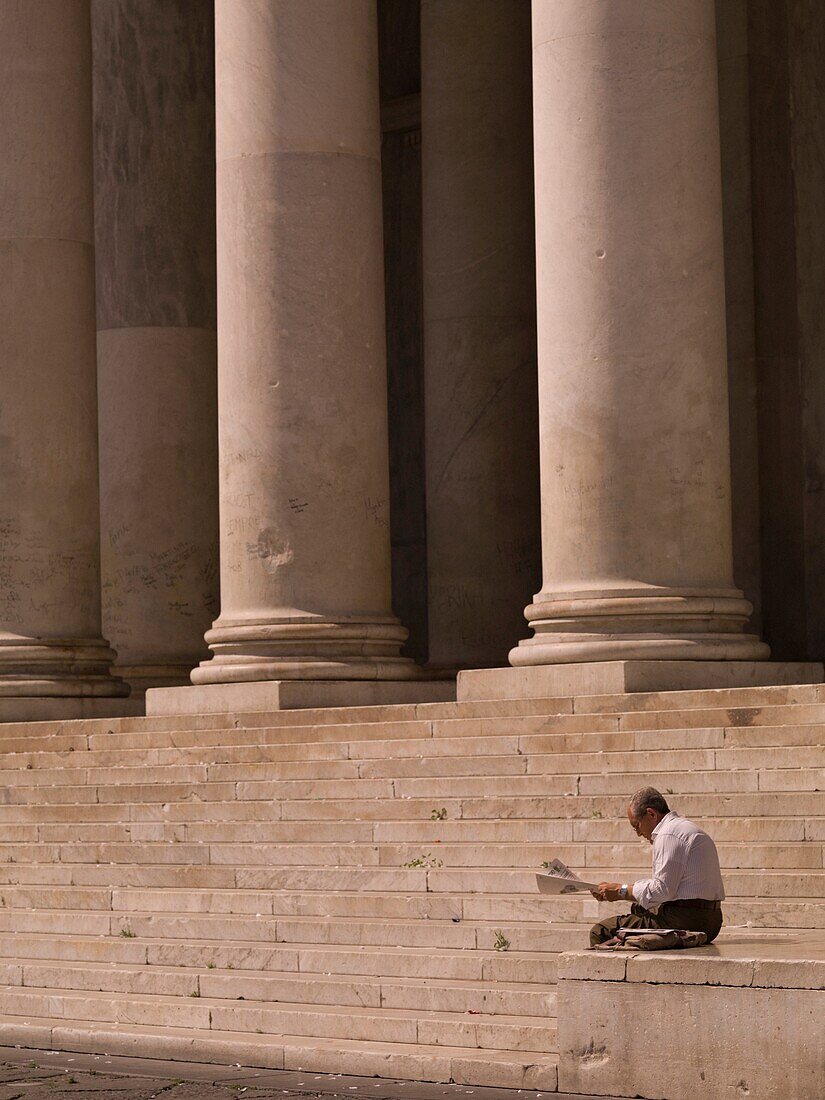 Mann beim Zeitungslesen, Treppe mit Säulen im Hintergrund; Neapel, Italien
