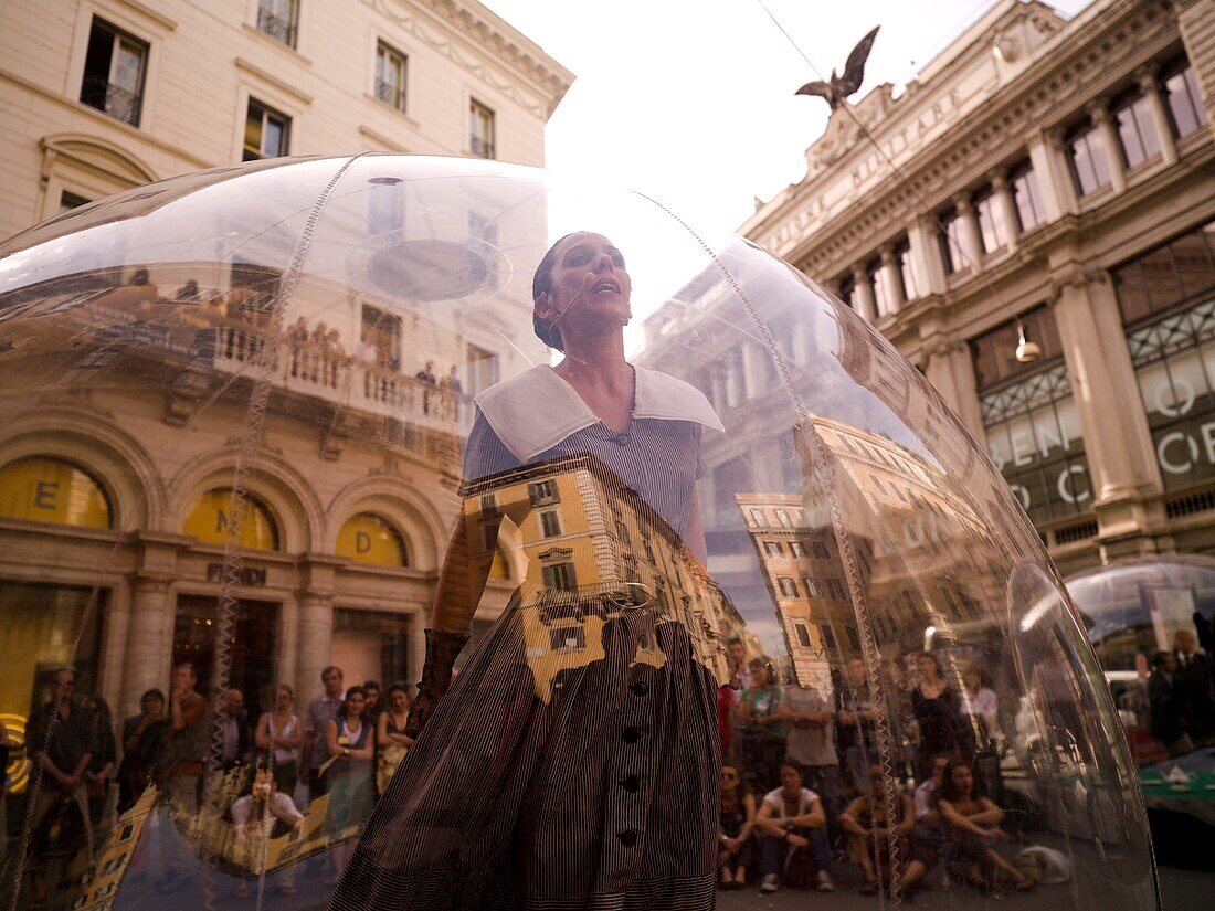 Woman Standing Inside Transparent Glass Globe And Crowd Watching Her Performance; Rome, Italy