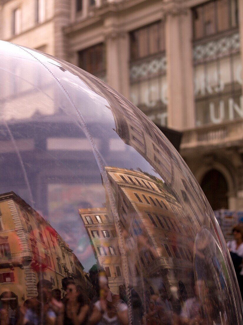 Close-Up Of Glass Globe With People And Buildings Reflecting In It; Rome, Italy