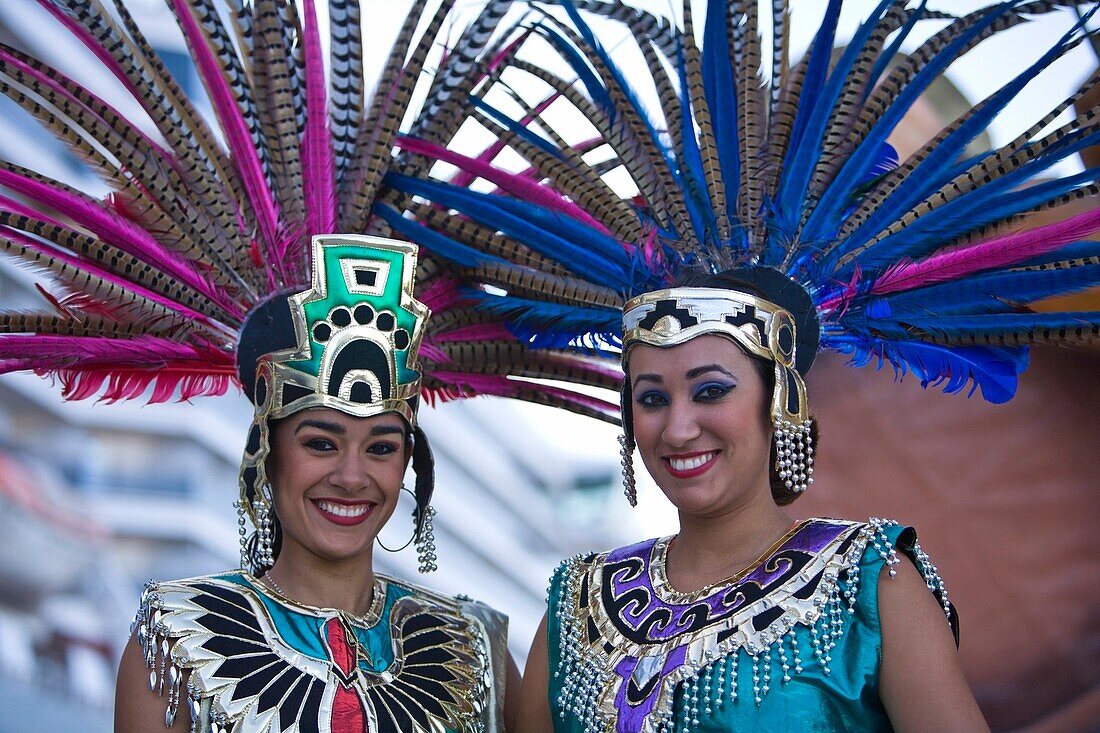 Zwei junge Frauen in aztekischer Kleidung, die einen Federkopfschmuck mit Fasanenfedern tragen, Kreuzfahrtterminal; Mazatlan, Sinaloa, Mexiko