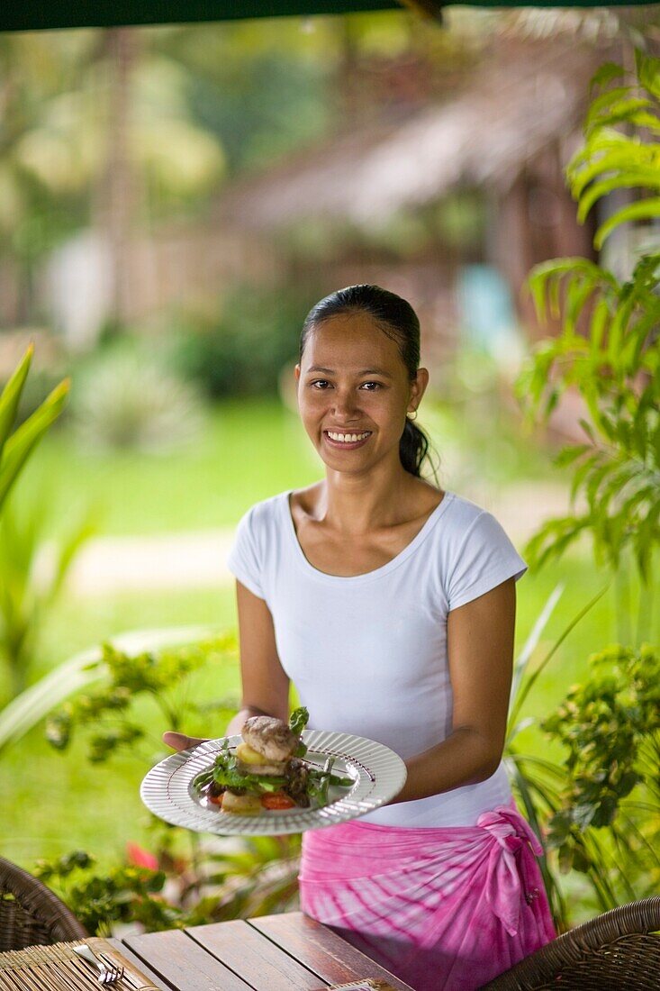 Junge Frau hält Teller mit Essen, Porträt; Dumaguete, Oriental Negros Island, Philippinen