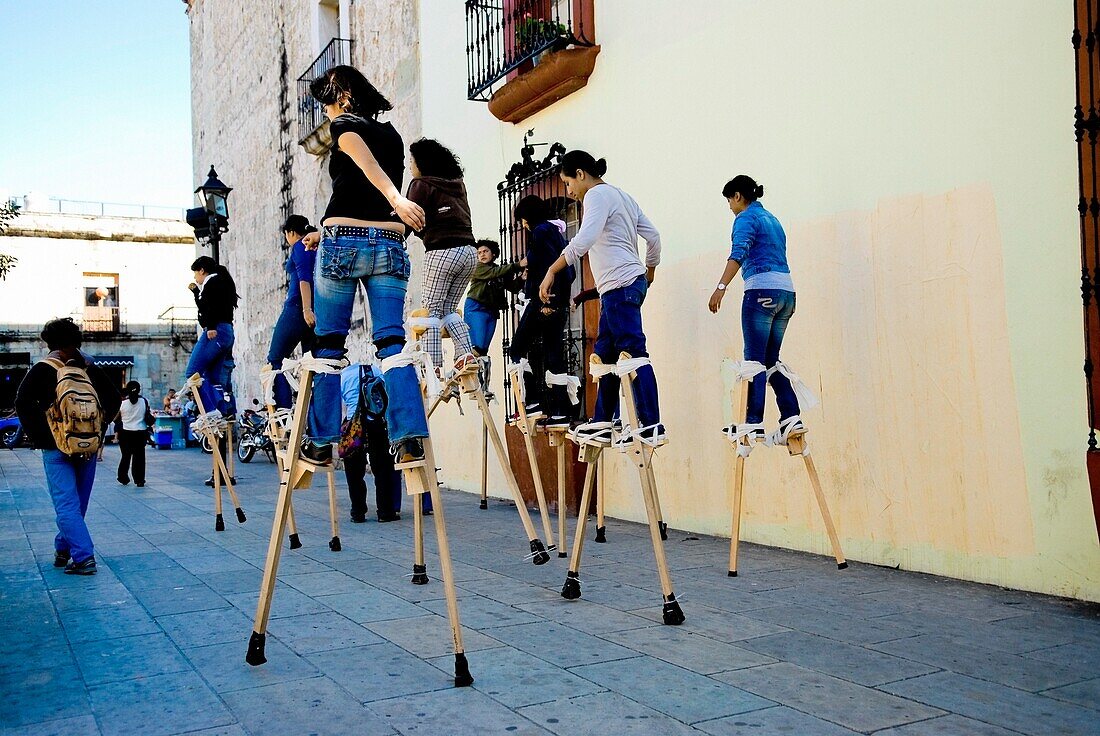 Mexico; Teenage Girls Walking On Stilts On Street
