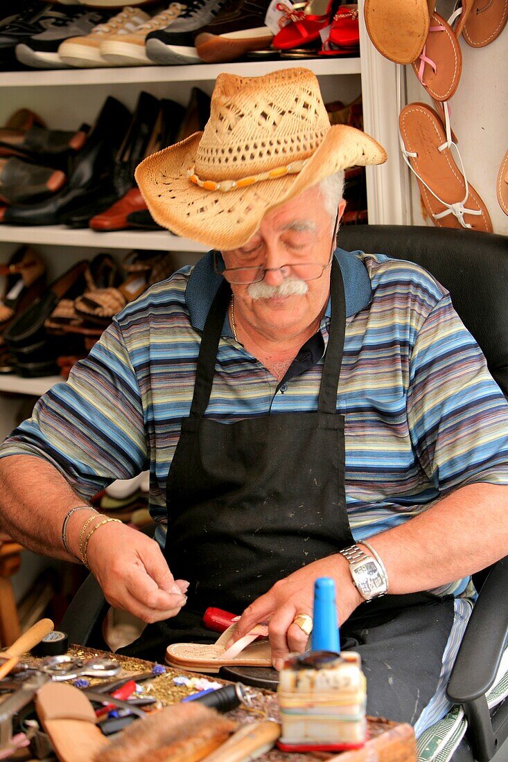 Capri, Italien; Älterer männlicher Handwerker bei der Herstellung von Ledersandalen