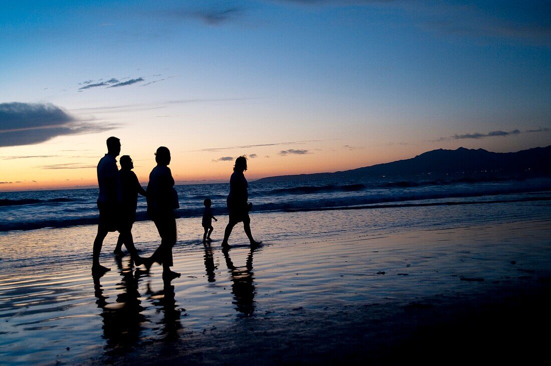 Puerto Vallarta, Mexiko; Menschen, die bei Sonnenuntergang am Meer entlang spazieren
