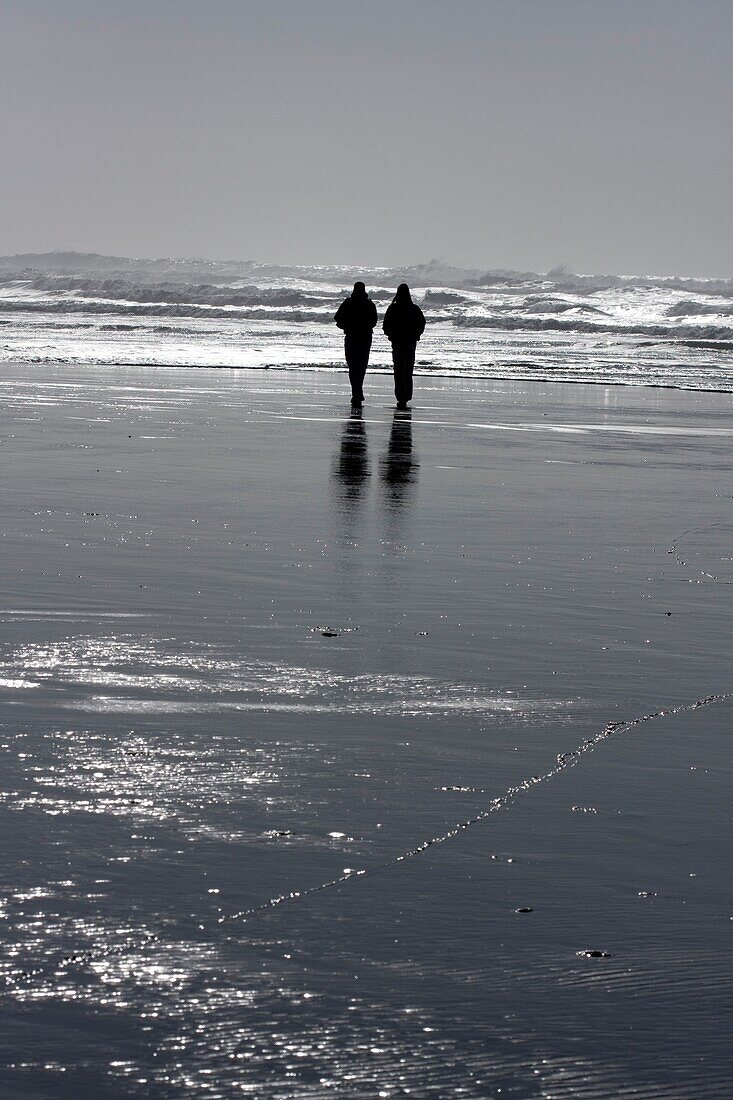 Zwei Menschen gehen am Strand spazieren