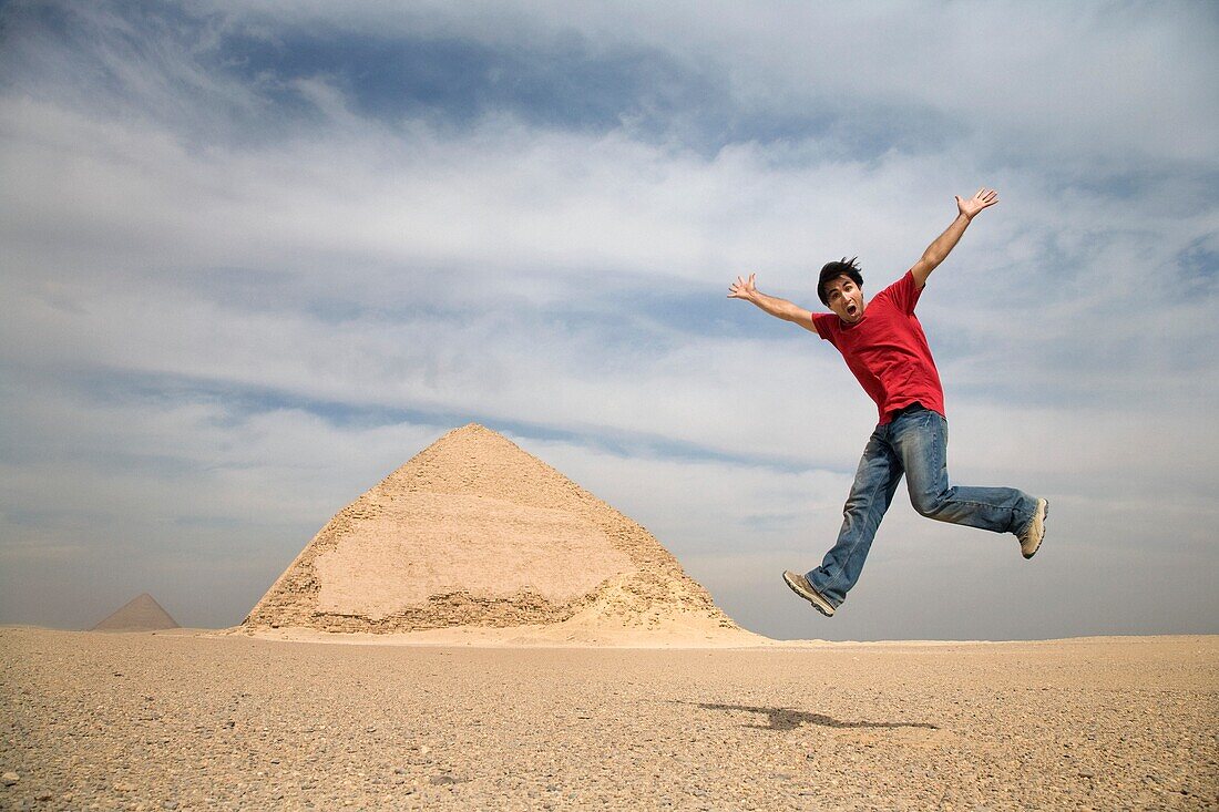 Mann springt in die Luft mit Pyramiden im Hintergrund; Kairo, Ägypten, Afrika