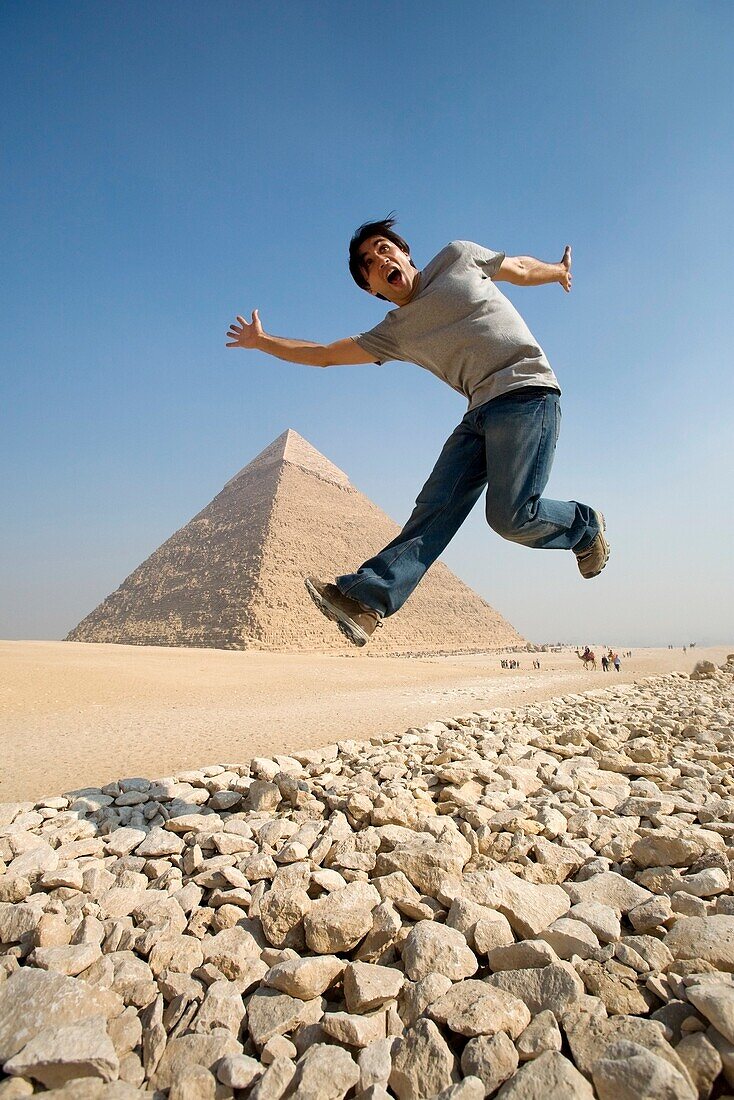 Ein Mann springt in die Luft mit einer Pyramide im Hintergrund