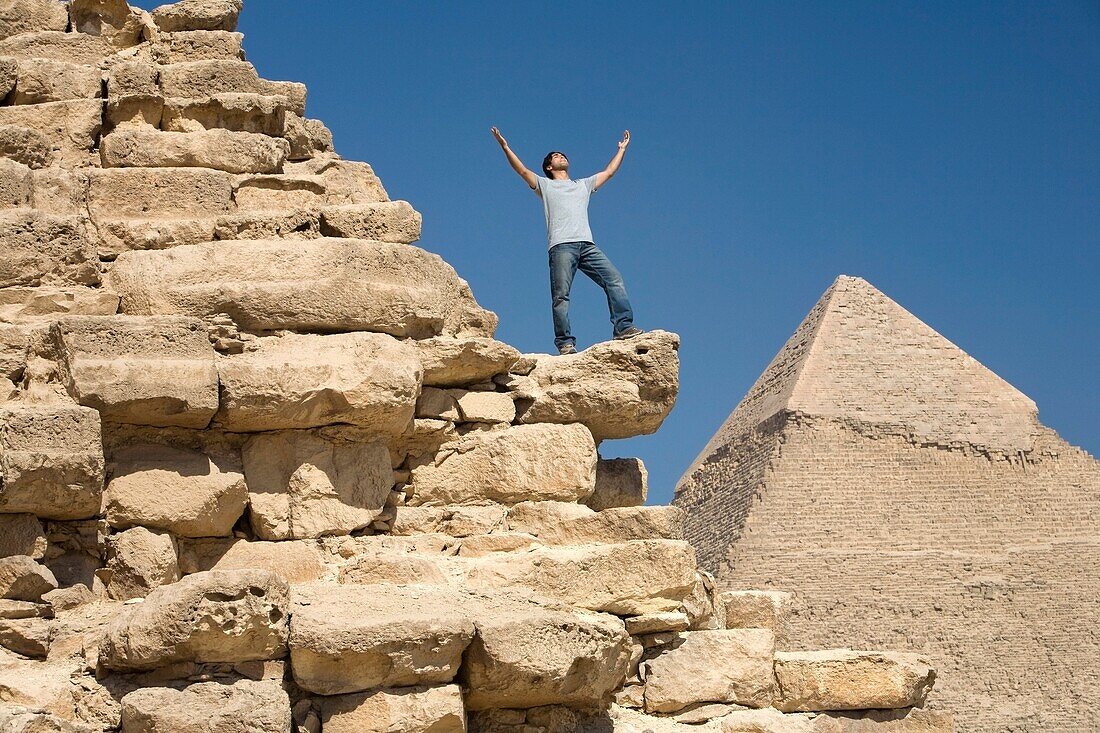 Man Standing On Part Of A Pyramid In The Desert; Cairo,Egypt,Africa