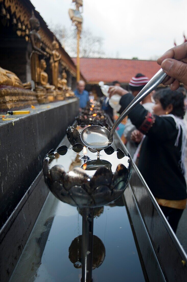 Gießen von Öl in Kerzen in einem buddhistischen Tempel, Chiang Mai, Thailand