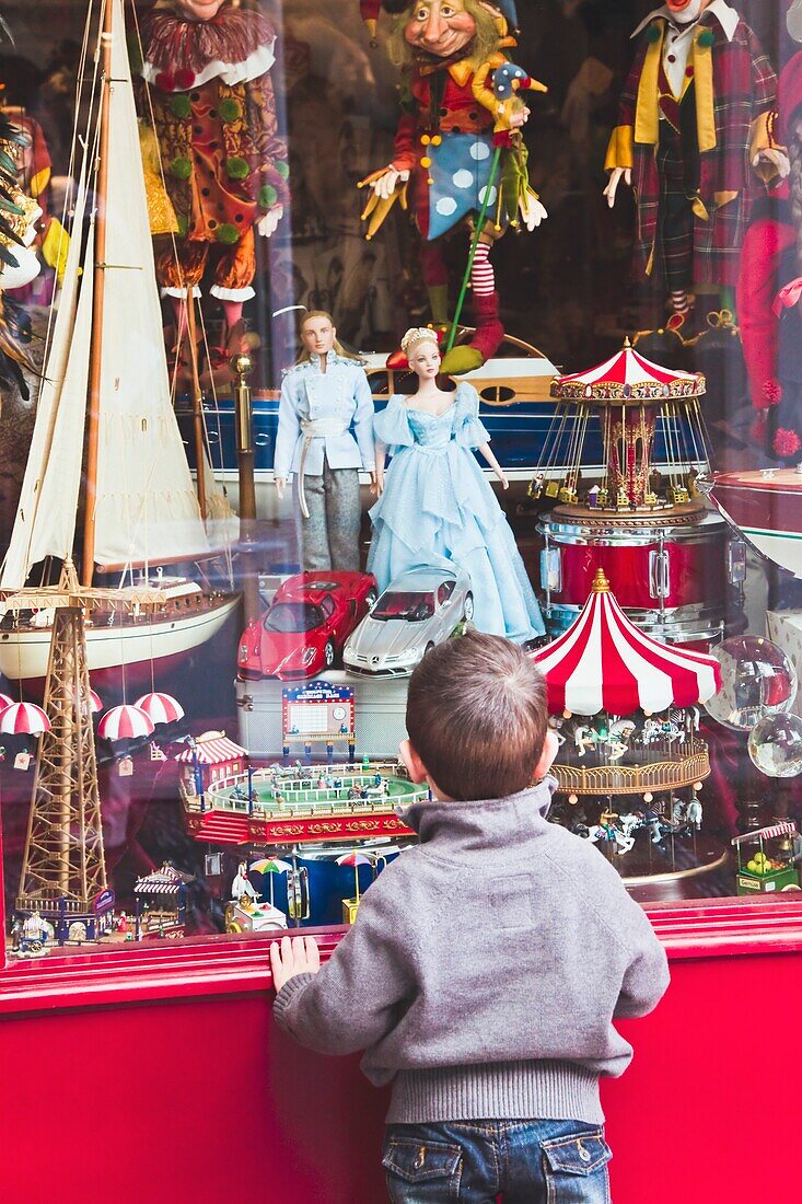 Kleiner Junge schaut in ein Spielzeugladenfenster