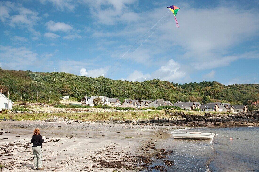 Frau lässt am Strand einen Drachen steigen, Insel Arran, Schottland