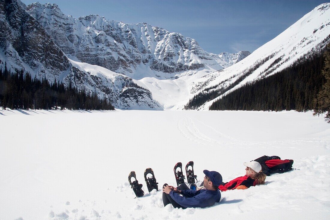 Paar auf Schneeschuhen, sitzend am Taylor Lake, Banff National Park; Banff National Park, Alberta, Kanada