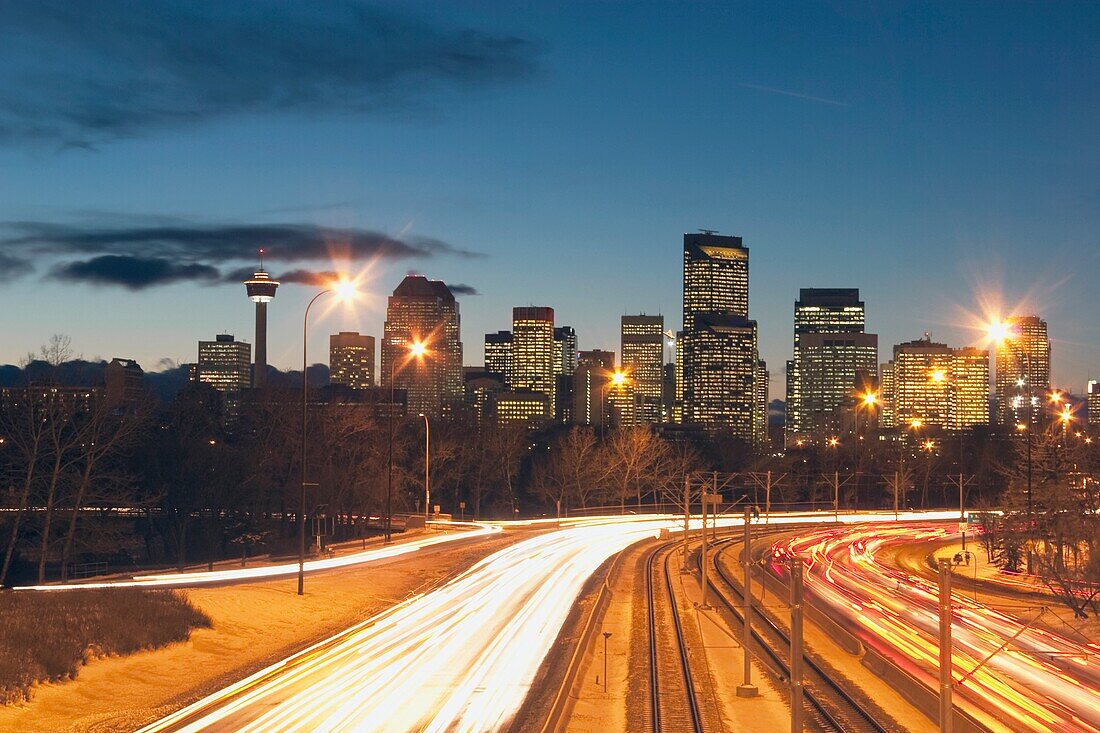 Calgary, Alberta, Kanada; Skyline bei Nacht mit Autolichtern auf der Straße