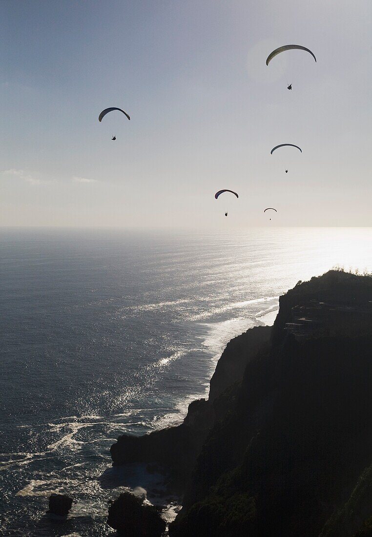 Gleitschirmflieger schweben frei über den Klippen der Bukit-Halbinsel in Bali, Indonesien