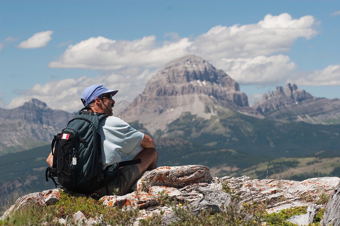 Crowsnest Pass, Alberta, Kanada; Ein männlicher Wanderer sitzt auf einem Bergrücken und betrachtet die Aussicht