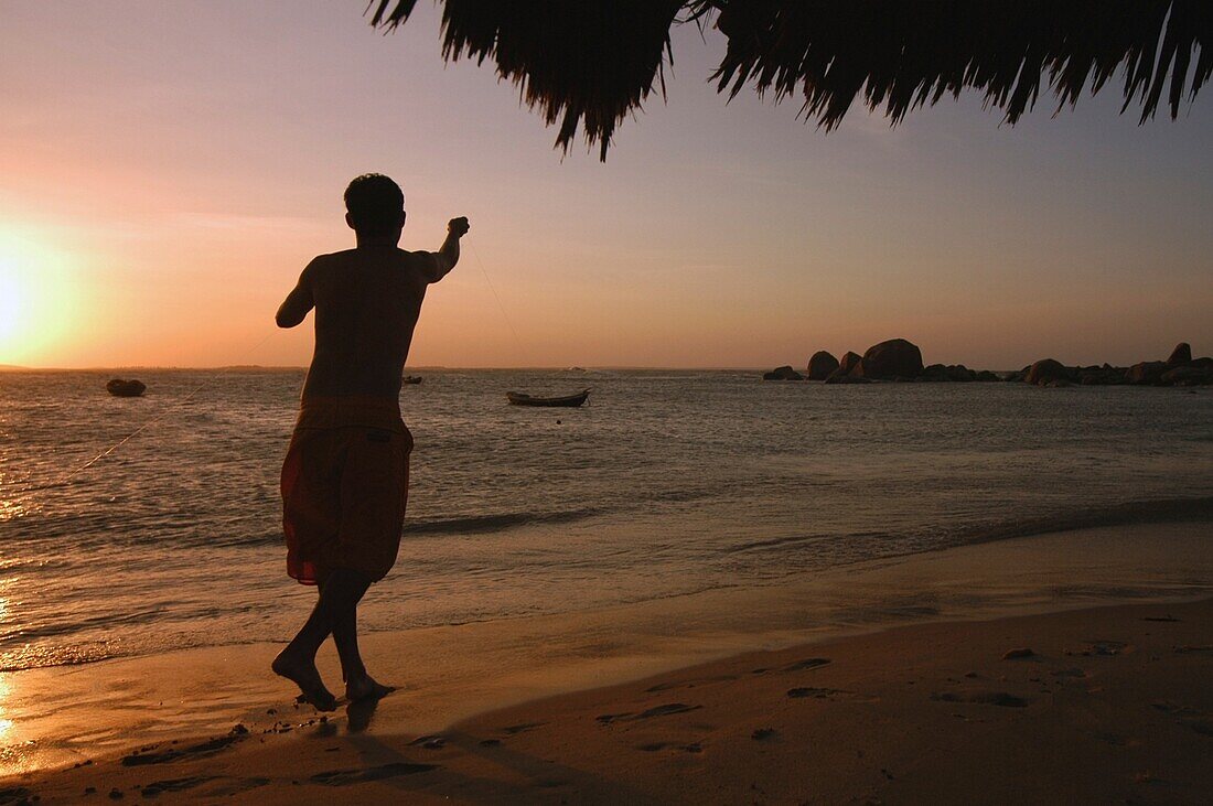 Junge geht am Strand entlang (Silhouette)