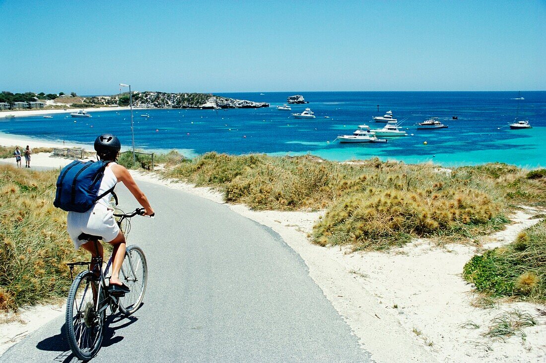 Female Tourist Cycling Along The Beach