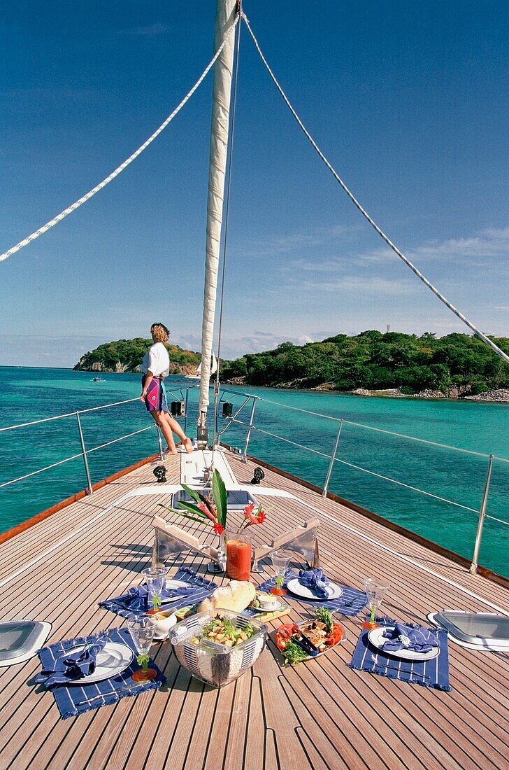 Essen auf dem Deck mit Frau im Hintergrund auf einer Yacht, die um die Grenadinen segelt