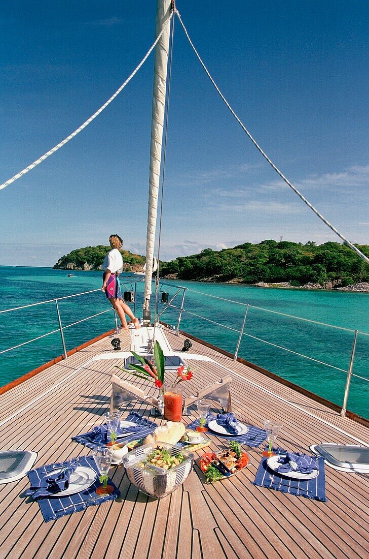 Food Set On The Deck With Woman In Background On A Yacht Sailing Around The Grenadines