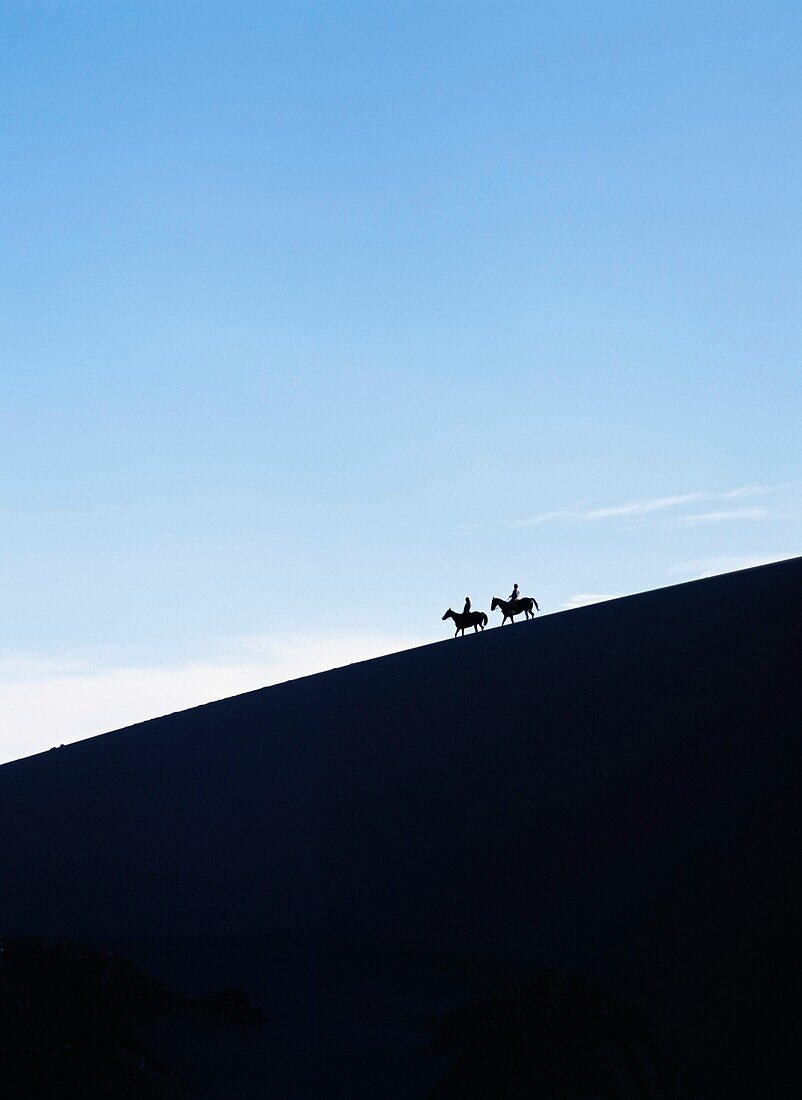 Silhouetted Horse Riders At Dusk On A Sand Dune In The Valle De La Muerte