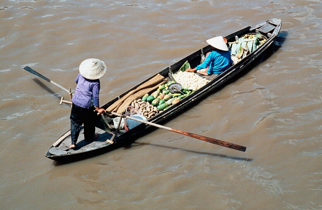 Frau, die Produkte auf einem Boot entlang des Mekong Flusses trägt