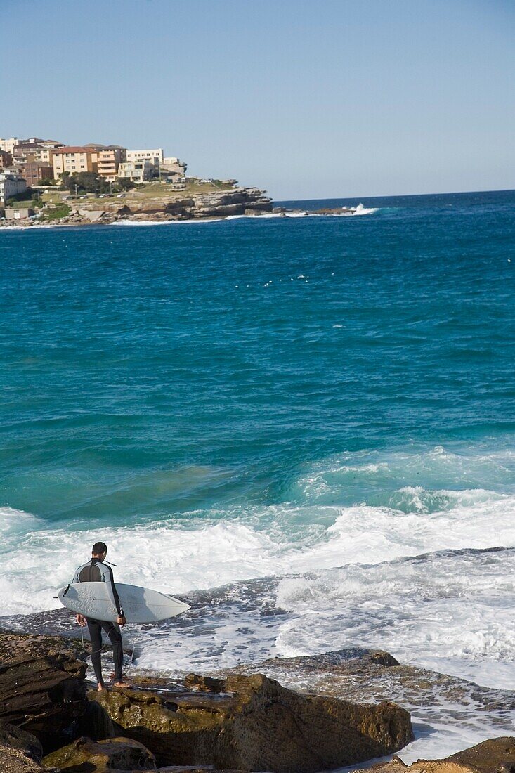 Male Surfer Standing On Rocks At Bondi Beach