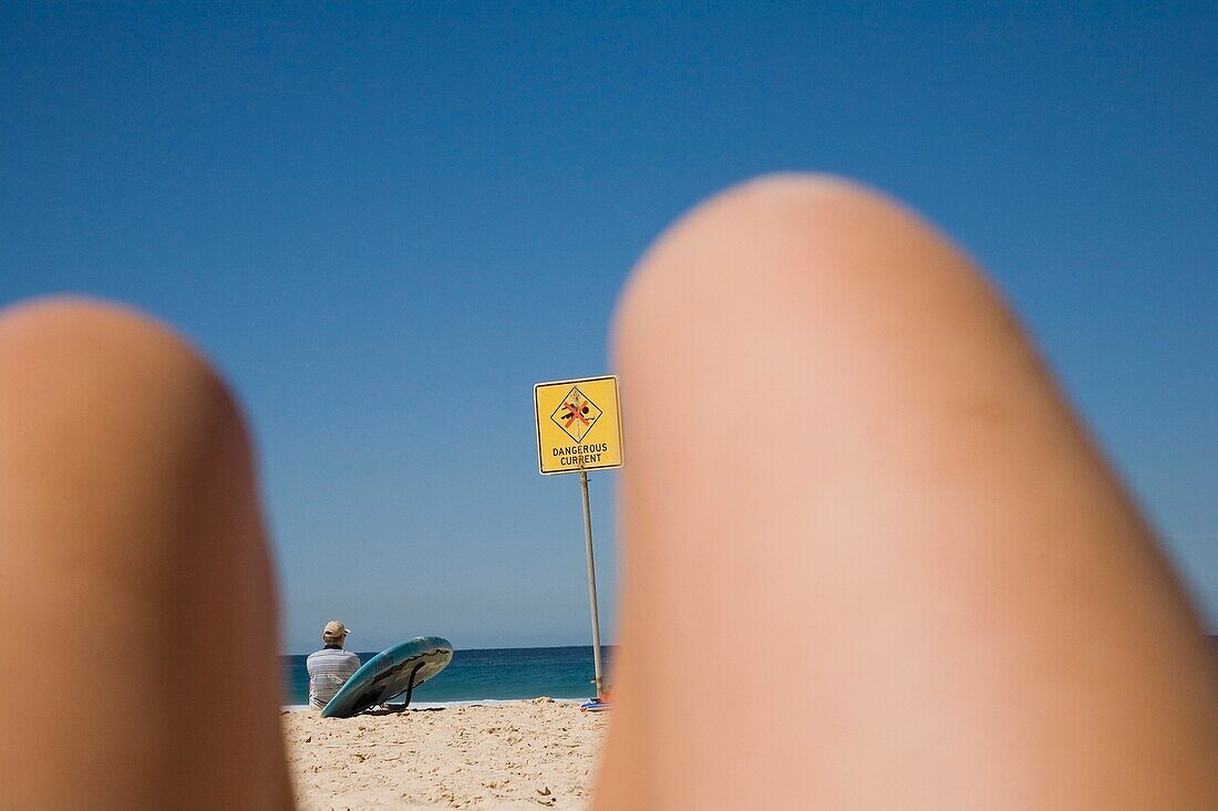 Surfer durch die Beine einer Frau am Strand von Bondi gesehen
