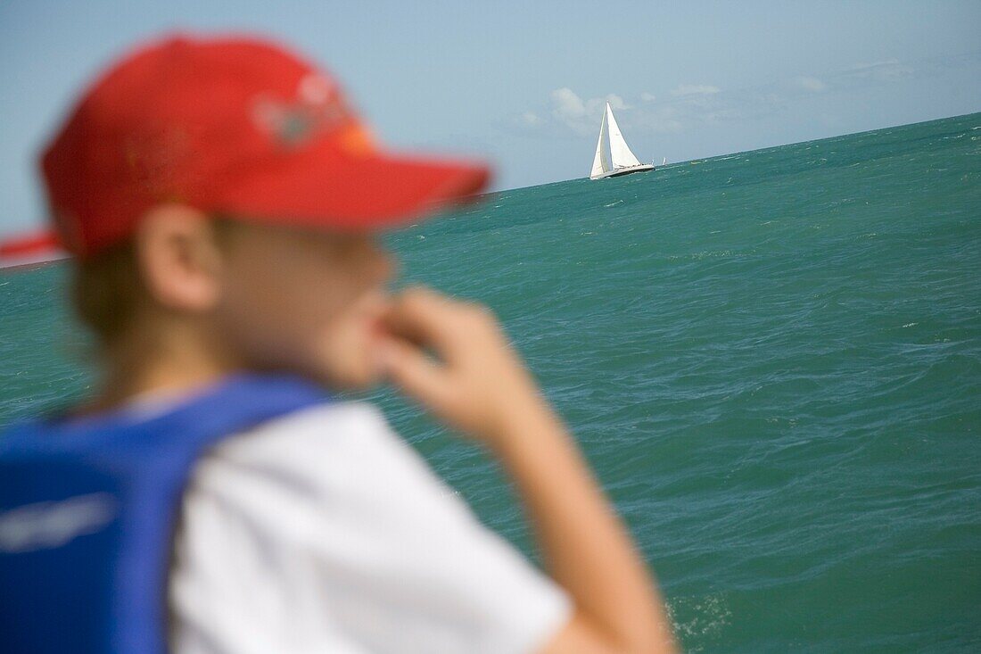 Junge mit Baseballmütze und Segelboot