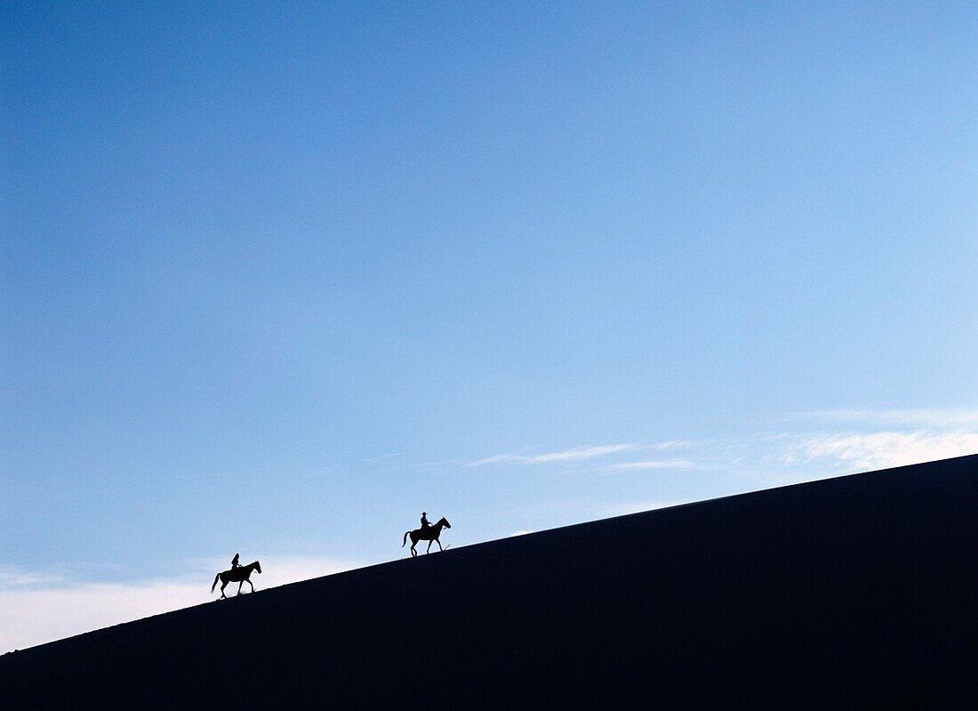 Reiter in der Abenddämmerung auf einer Sanddüne im Valle De La Muerte in den Cordillera De La Sal Mountains