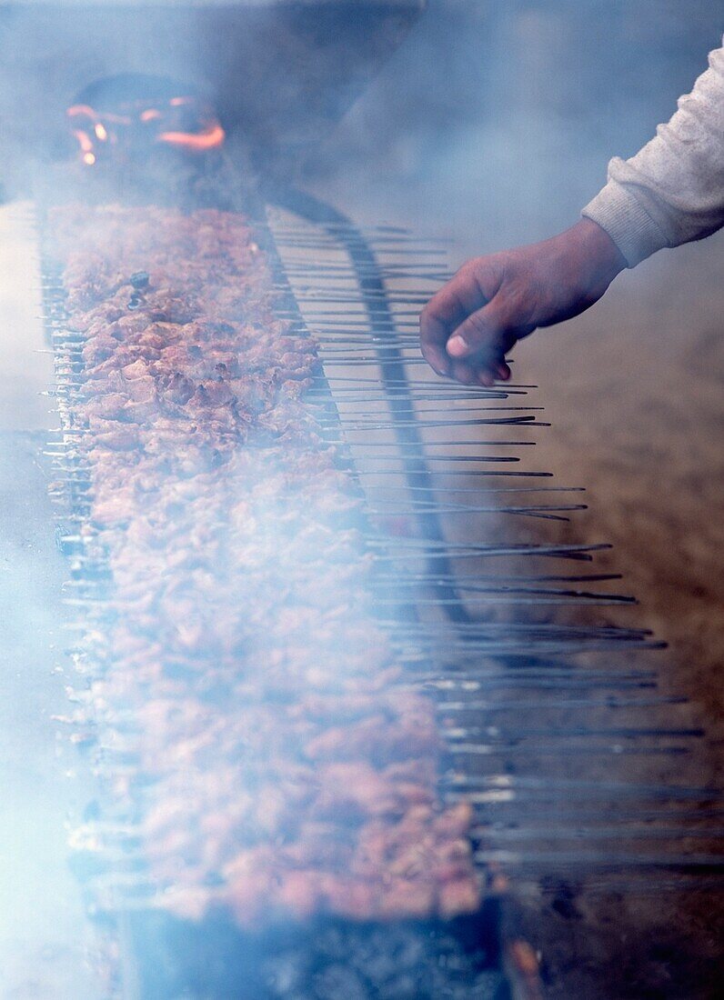 Mann mit Lammkebabs auf dem Sonntagsmarkt in Hotan