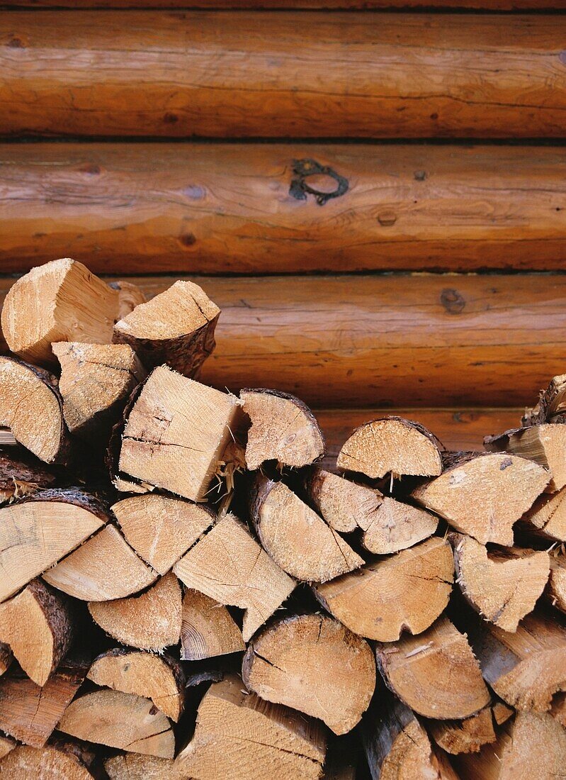 Aufgestapelte Baumstämme vor einer Blockhütte, Kanada