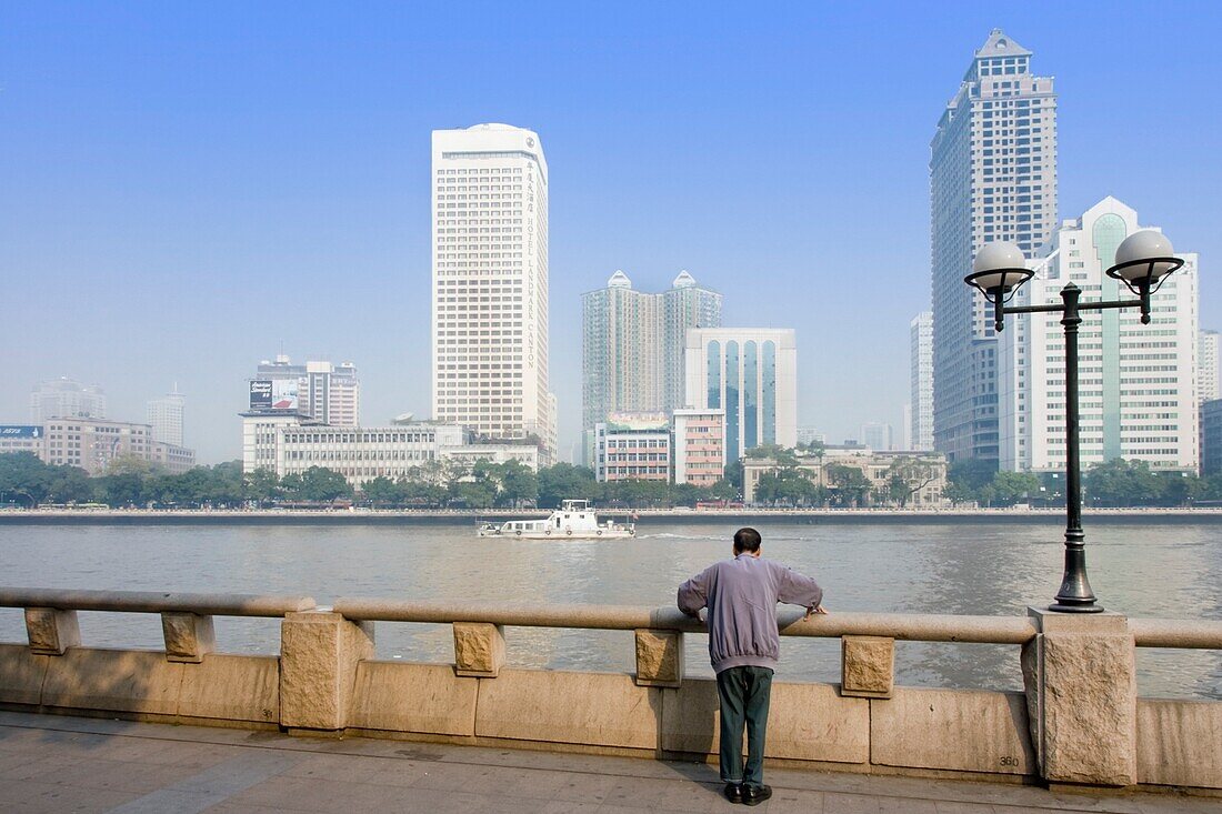 Mann am Fluss mit dem Geschäftsviertel von Guangzhou im Hintergrund stehend