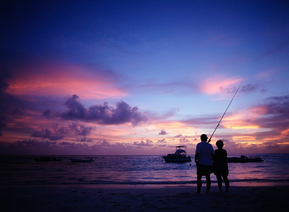 Ehepaar mit Angelrute beobachtet den Sonnenuntergang