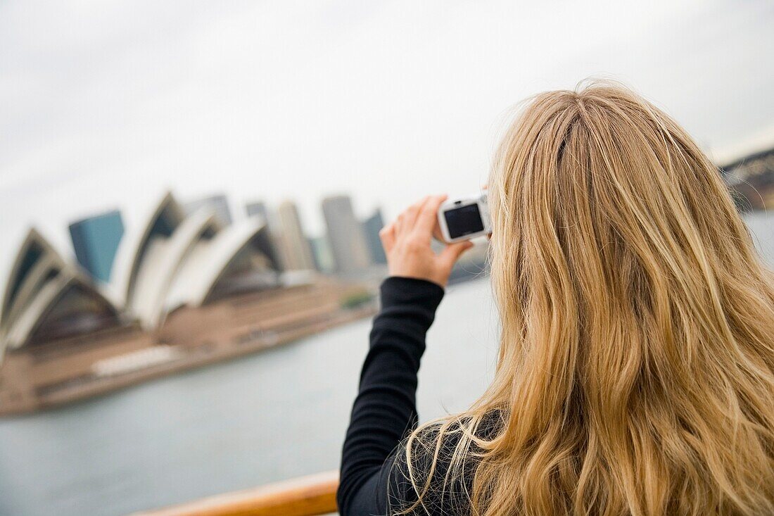 Frau fotografiert das Opernhaus von Sydney von der Fähre aus