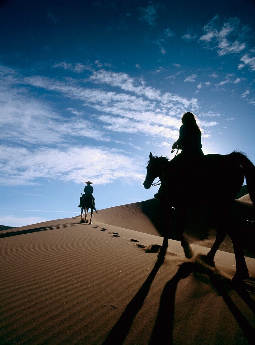 Horseback Riders In Silhouette On Sand Dune