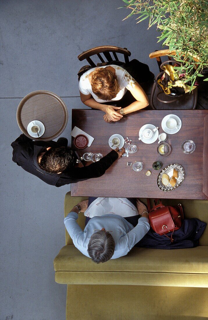 Blick von oben auf einen Kellner, der einen Tisch im Café abräumt