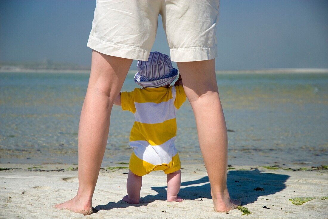 View Of Baby And Mother's Legs On Beach