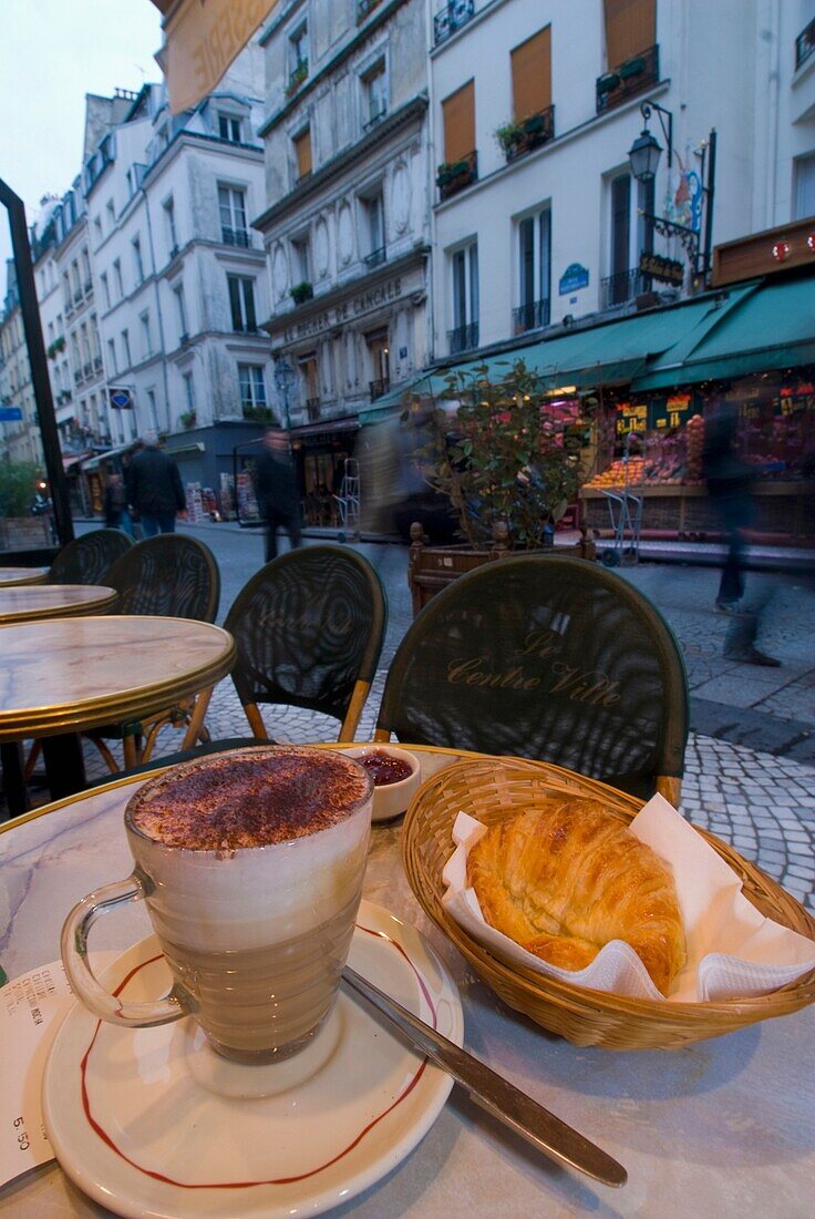 Kaffee und Croissant am Tisch auf dem Bürgersteig im Café in der Rue Montorgueil früh am Morgen.
