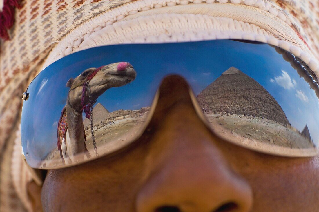 Kamel und Pyramiden spiegeln sich in der Sonnenbrille eines Einheimischen