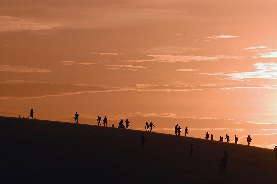 People In Silhouette Climbing Sand Dunes