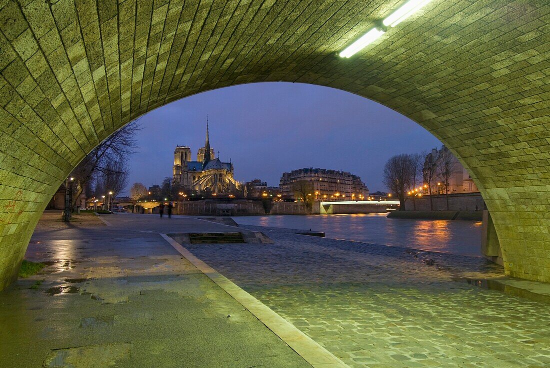 Bogengang unter der Brücke mit Blick auf die Kathedrale Notre Dame in der Abenddämmerung.