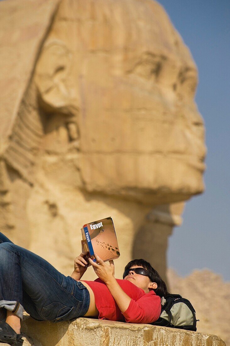 Tourist auf dem Rücken liegend und Reiseführer lesend, Große Sphinx im Hintergrund