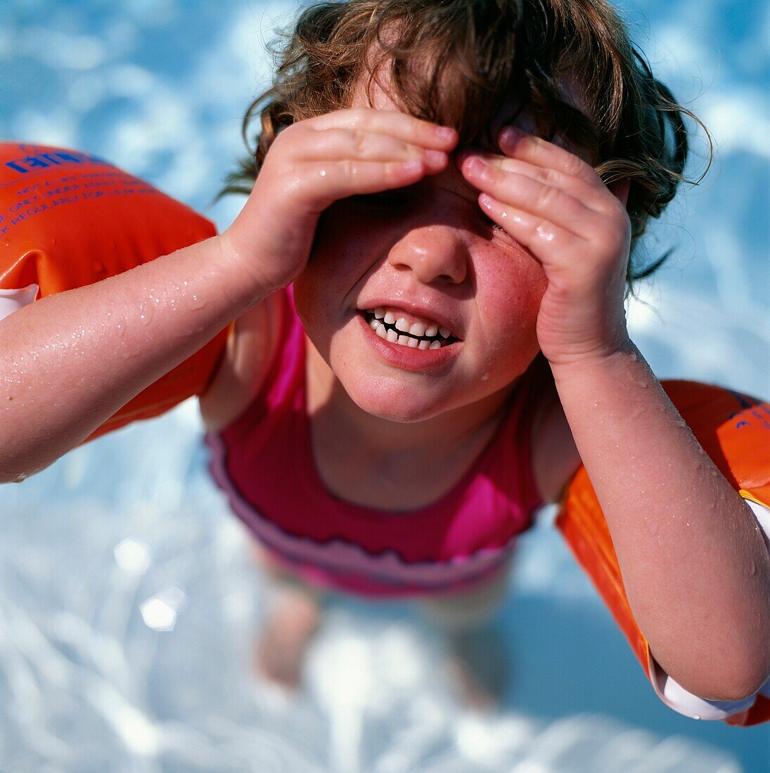 Junges blondes Mädchen mit Schwimmarmbändern in einem Pool