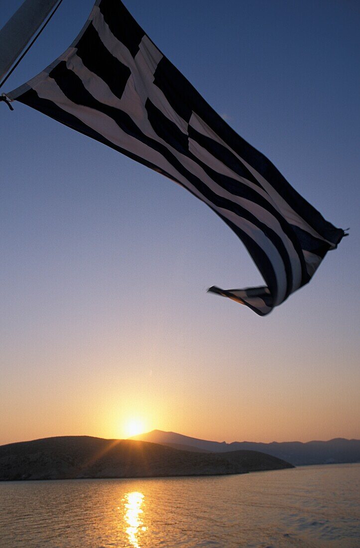 Griechische Flagge über dem Meer bei Sonnenaufgang